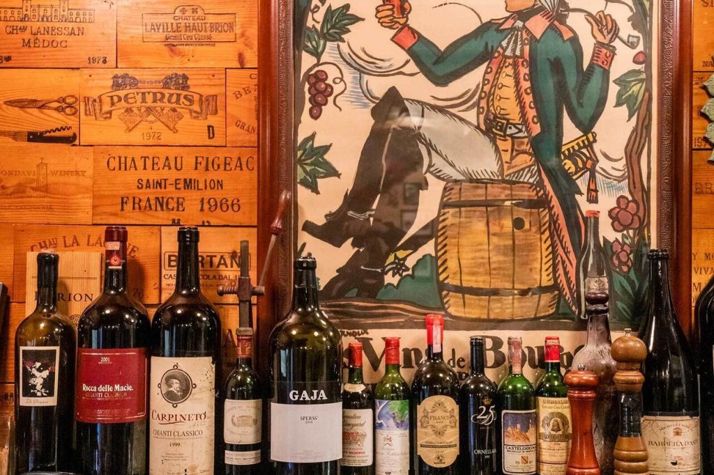 Assorted wine bottles displayed in front of a vintage mural